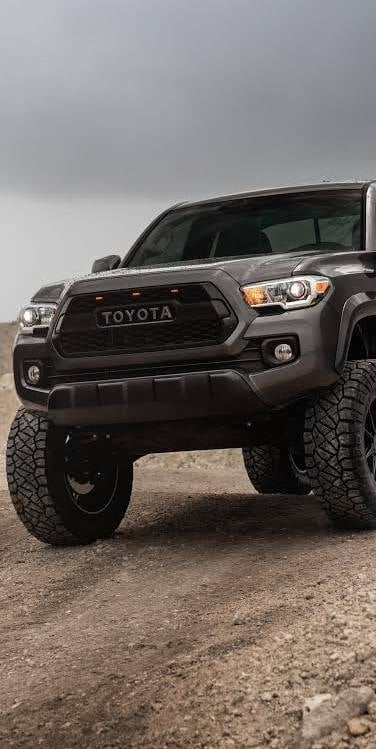 Gray Toyota Tacoma TRD pickup truck with lifted suspension and all-terrain tires parked on desert dirt road