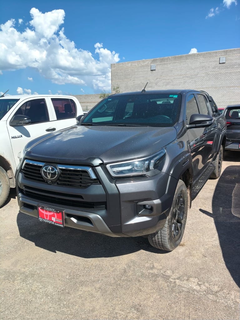 Gray Toyota RAV4 parked in a lot with other vehicles and a brick building in the background
